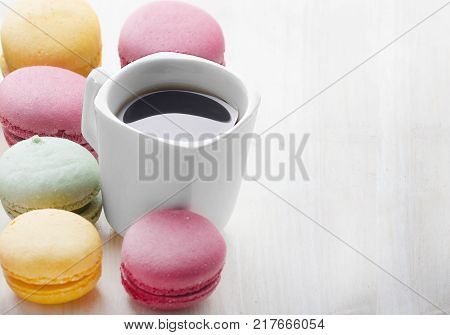Dessert macaroons with a cup of black coffee. Multicolored cakes. Tasty breakfast.