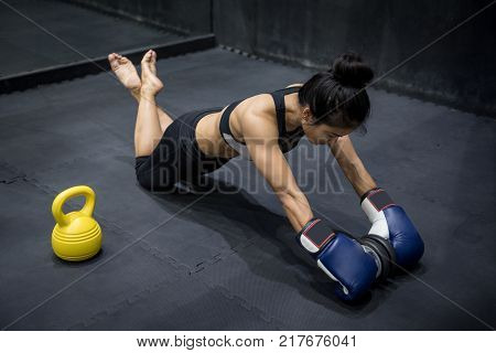 Young Asian Boxer woman doing exercise with rolling dumbbell and kettlebell in fitness gym. Healthy lifestyle with muscle build or bodybuilding