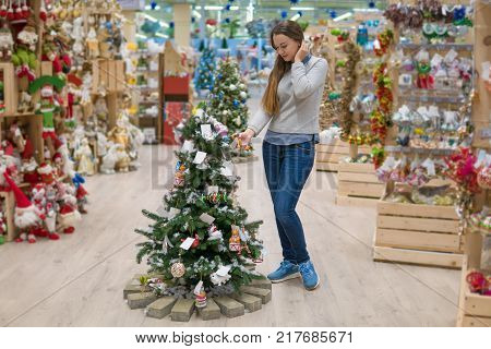 Cheerful happy customer girl choosing Christmas tree for the new year on Christmas Eve. difficult decision. Various choice