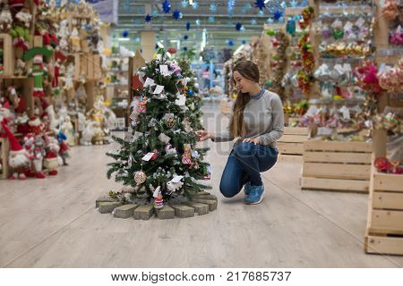 happy customer girl choosing Christmas tree for the new year on Christmas Eve. New year shopping