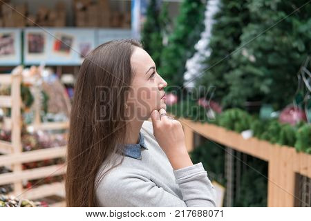 smart customer girl choosing Christmas tree for the new year on Christmas Eve. difficult decision. Various choice