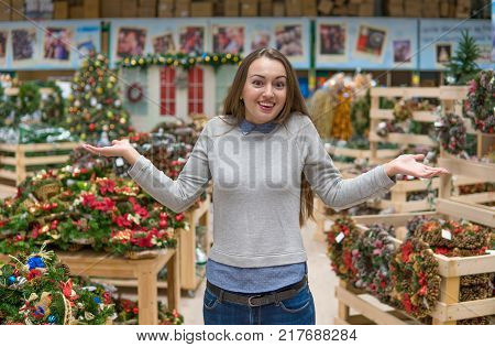 Cheerful girl choosing gifts for Christmas and New Year. she is at a loss from the variety of goods. difficult decision. She shows wondered emotion