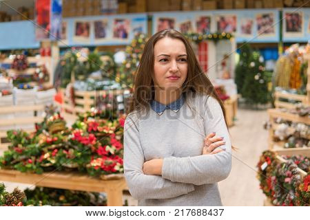 Emotional customer choosing gifts for Christmas and New Year. she is sad because of the variety of goods. she doesn't like shopping