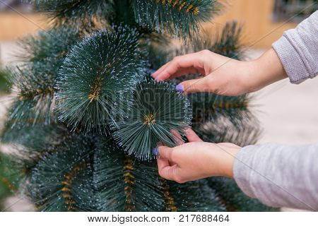 closeup view of hands choosing faux Christmas tree on Christmas Eve. Save nature concept