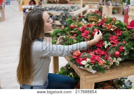customer woman choosing Christmas decorations. Various choice of New Year's wreath with decorations