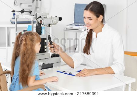 Ophthalmologist inspecting eye fundus of little child in clinic