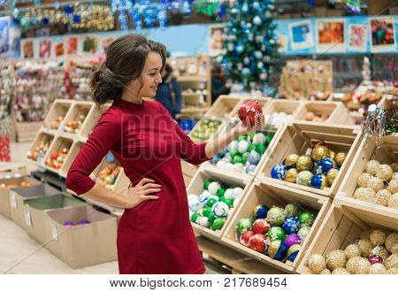 Luxury stylish customer woman choosing gifts for Christmas and New Year. She is taking red Christmas tree decorations. difficult decision. Various choice
