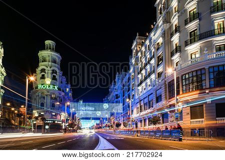 Madrid, Spain - December 8, 2017: Gran Via Street in Madrid at night on Christmas time. Long exposure shot with light trails of traffic and blurred people