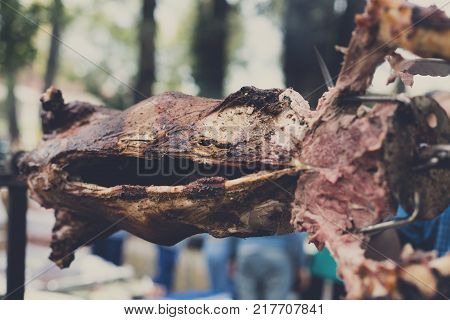 Whole lamb roasted at spit, barbecue. Grill, big piece of meat at rolling skewer. Street vendor food. Catering concept