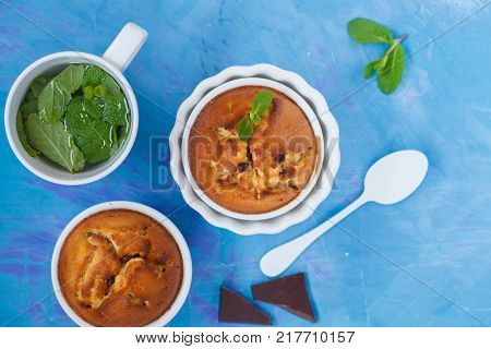 Chocolate cupkakes with mint tea blue background top view. Sweet home-cooked concept.