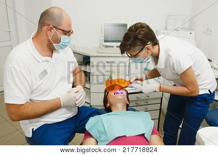 Process Of Preparing And Installing Dental Ceramic Crown. Male Professional Dentist And Female Assis