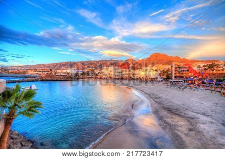 Beautiful view over Pinta beach at sunset with colorful water and sea and architecture illuminated by sunshine in Tenerife, Canary island of Spain
