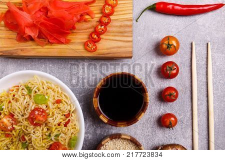 A top view on a chinese food. Chilli, soy and rise sauce, chopsticks, tomatoes on a rise nuddles on the marble background. Close-up of objects. Food concept.