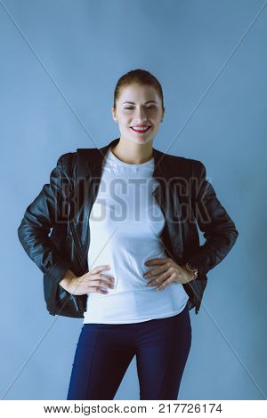 Portrait of beautiful young brunette woman in stylish black jacket on gray