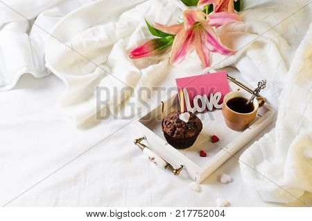 Muffins or capkakes with chocolate and black coffee on a wooden tray in bed. White background. Sweet food. Festive mood copy space flat lay