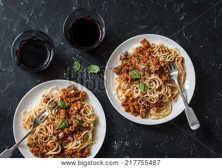 Chicken bolognese spaghetti and glasses of red wine on dark background top view. Delicious lunch in a mediterranean style top view. Flat lay