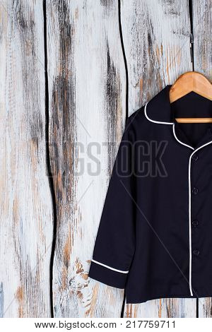 Classic navy pajama shirt. Unisex sleeping garment on wooden hanger. Sleepwear and robes.