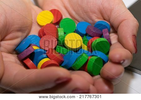 hands of a woman holding gambling, multicolored, wooden chips
