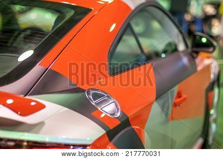 red racing sports car shines and shimmers in the lights of the auto show back view