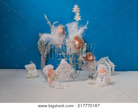 Christmas card. Group of angels and fluffy trees on a blue background