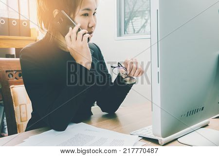 Businesswoman talking moblie phone at her working space in the office business busy concept