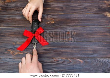 Woomen give car key. Woman hand hold car key with red bow. Giving a car as a gift.