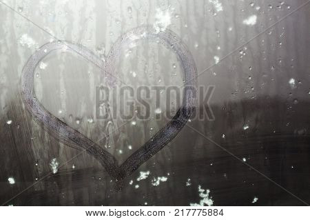 Sticky snow on a hand-drawn heart on the sweaty glass
