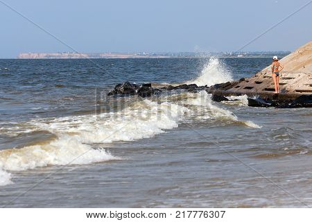 Lonely young woman stand in deserted beach alone. Early morning. The sea after the storm with dirty water. Deserted beach in Ochakov in July 2017