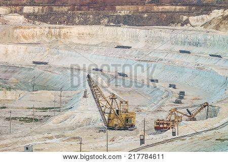 Work of heavy grapple excavators in a deep chalk quarry. Mining industry. Big clamshell excavators in the lowland quarry.