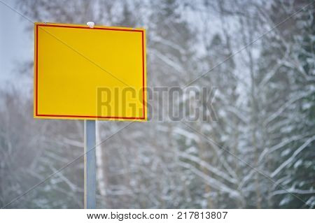 Yellow empty direction sign on winter forest background