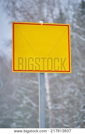 Yellow empty direction sign on winter forest background on vertical shot