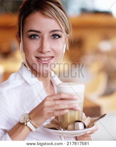 Beautiful blond woman smiling while listening to music with  hea