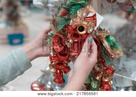 Closeup view of hands choosing Christmas tree or New Year's decoration bells. Holidays mood