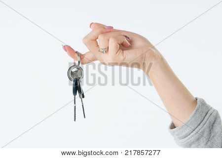 Hand of business woman or real estate agent with keys from new flat or house hanging on the finger. She welcomes to buy a flat or house. Isolated on white background