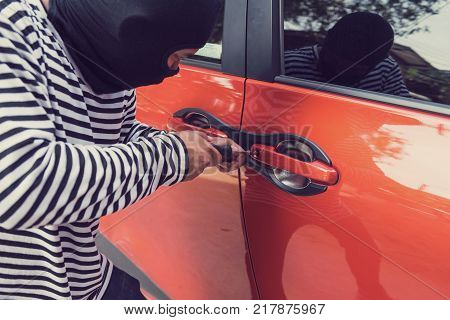 Car thief trying to unlock a car by screwdriver.