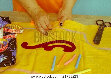 Woman's hand sewing fabric with sewing equipments. female in costume sewing