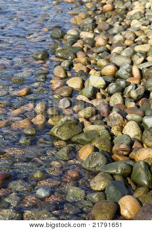 Vatten rullar försiktigt över stenar på en stenig strand