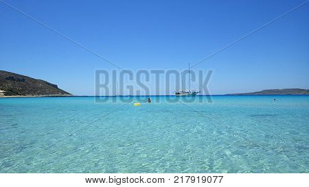 Pure clear azure sea water and sailing boat on the Simos beach, Elafonisos island, Peloponnese, Greece