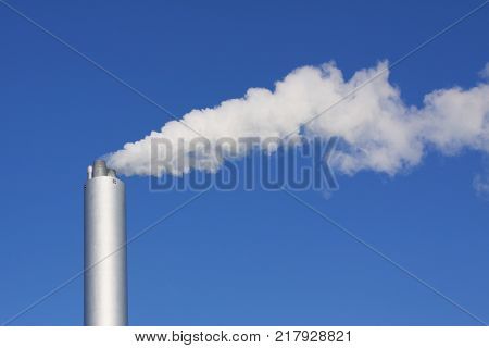 Cloud of white smoke from industrial chimney against blue clear sky with copy space
