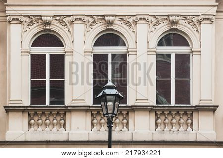 Three windows on the facade of an old vintage house a street lamp on a foreground