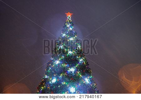 Decorated Christmas tree with star on the top in snowfall