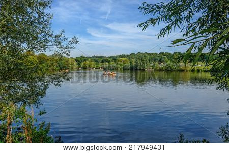 Hainault Forest Essex UK - August 28 2017: Girls in a rowing boat on the lake in the forest. Bright blue sky day.