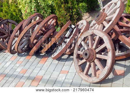 A lot of wooden wheels from old carts in disorder piled in the yard.
