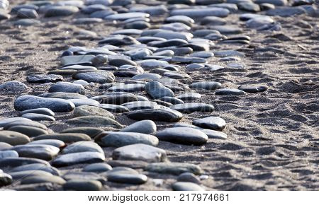 Stones in sand on the seashore. Background of the Gray Stones.Old Gray Stones