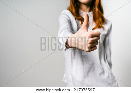 red-haired woman in white shirt shows thumb up
