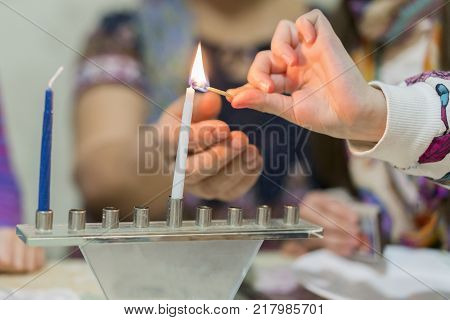 An Israeli 8 year old child lighting a Hanukkah Menorah