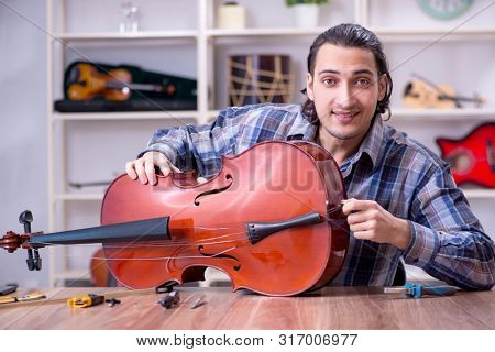 Young handsome repairman repairing cello