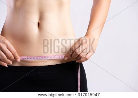 Closeup Of Woman Showing On Her Belly Dark Scar From A Cesarean Section With Measuring Tape. Healthc