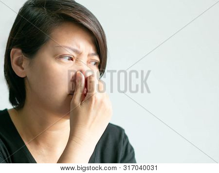 Close-up Of Caucasian Woman Use Thumb And Forefinger Pinch Her Nose When Scent Bad Smell; Or Getting