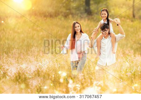 Asian Family Father, Mother And Daughter Play Togather In The Outdoor Park With Sunrise And Goldent 
